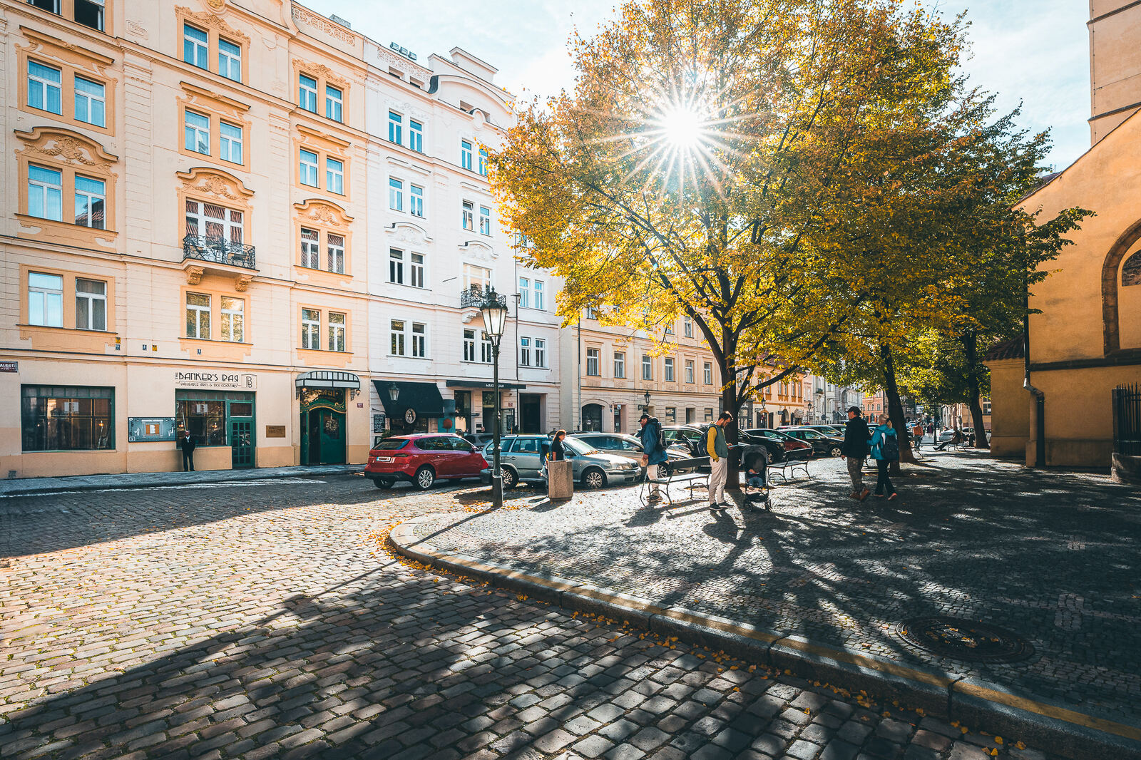 Autumn sunlight through a tree on a cobbled square near Hotel Haštal in Prague