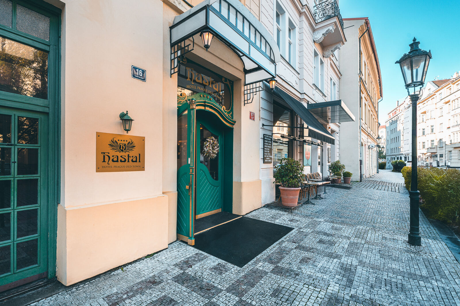 Green entrance door of Hotel Haštal Prague on a quiet cobbled Old Town street with a street lamp
