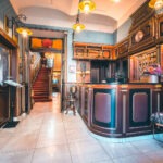 Wood-panelled lobby with a reception desk and red-carpeted staircase at Hotel Haštal Prague