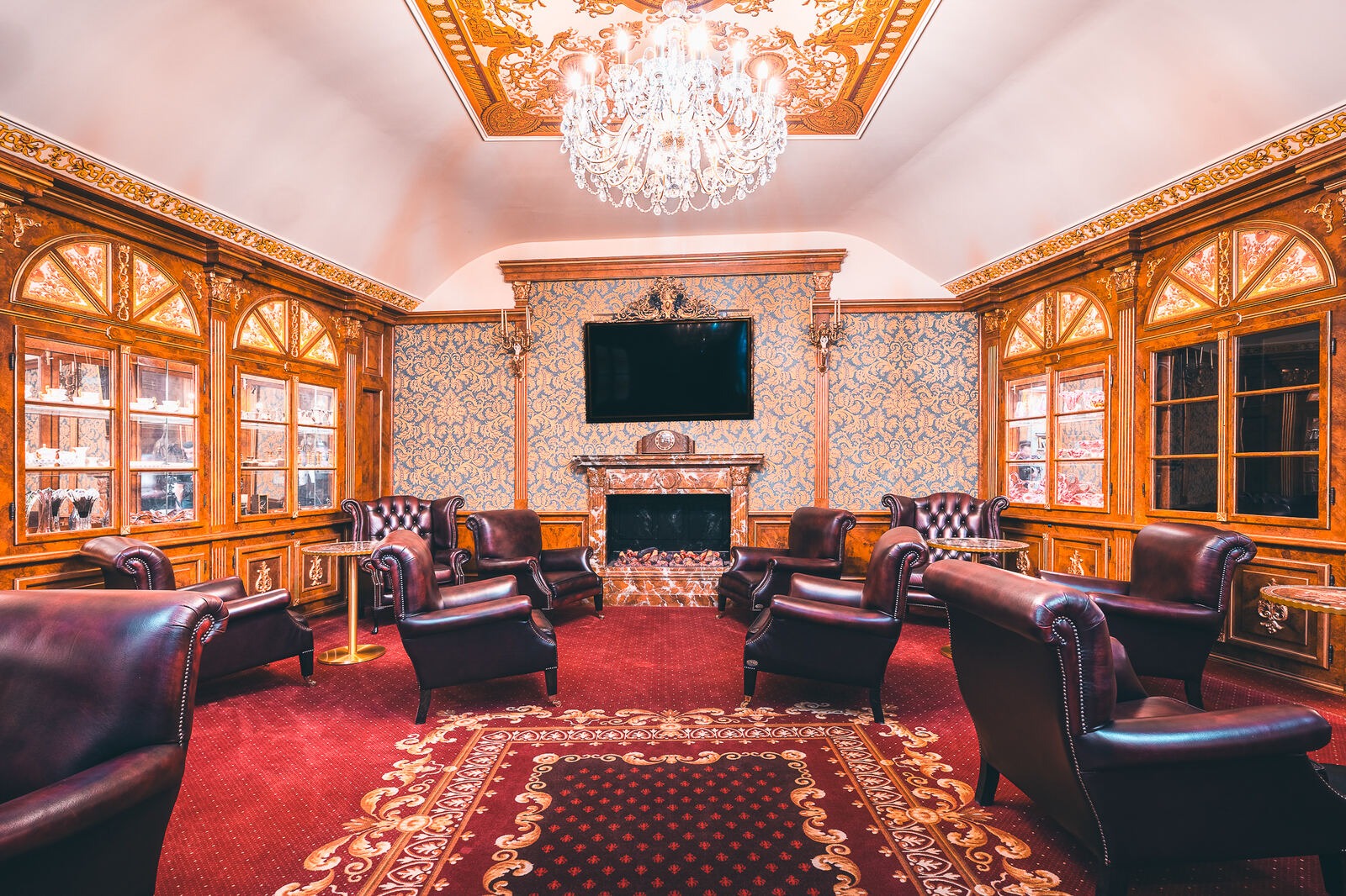 Wood-panelled lounge with a chandelier, leather armchairs and a fireplace at Hotel Haštal Prague
