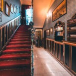 Staircase with a red carpet and framed historic pictures at Hotel Haštal Prague