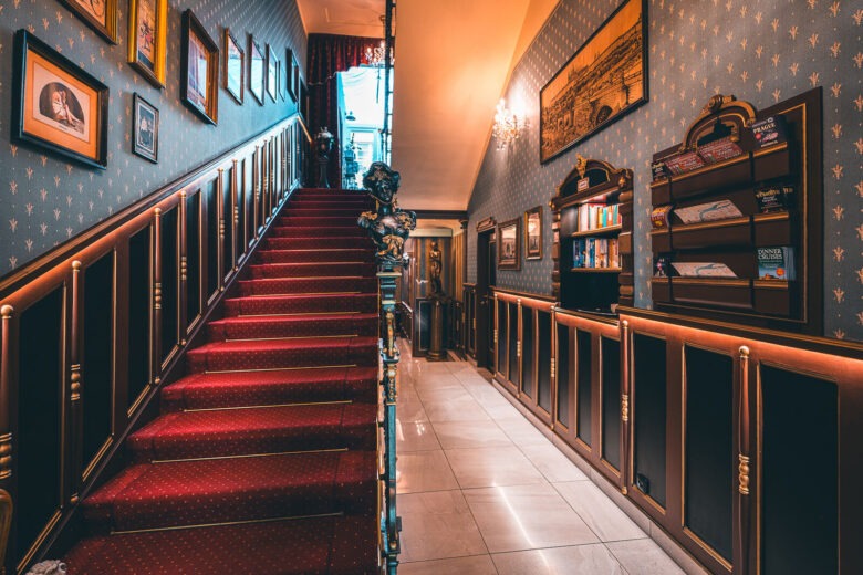 Staircase with a red carpet and framed historic pictures at Hotel Haštal Prague