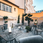 Sunny courtyard terrace with tables, flowers and a champagne bucket at Hotel Haštal Prague