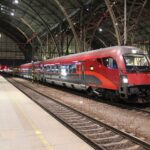 Red Railjet train standing at a platform under the roof of Prague main station