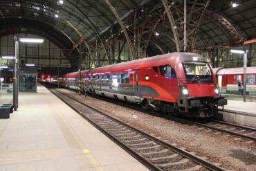 Red Railjet train standing at a platform under the roof of Prague main station